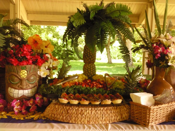 Centerpiece made of stacked pineapples shaped like a palm tree, next to a fruit tray