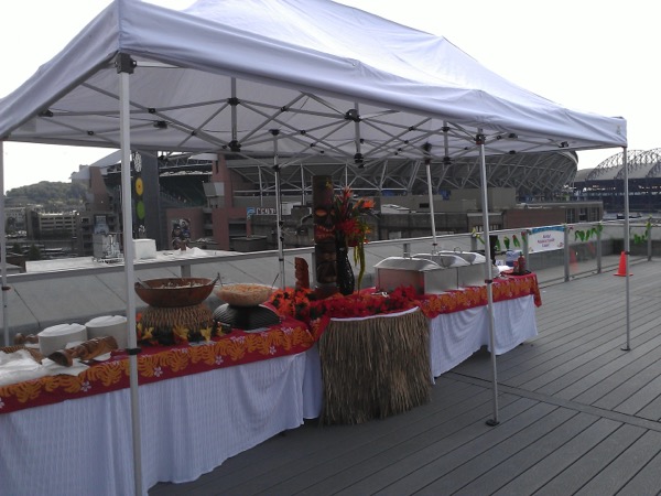 Catering tent set up on a rooftop event space with a stadium and city skyline in the background